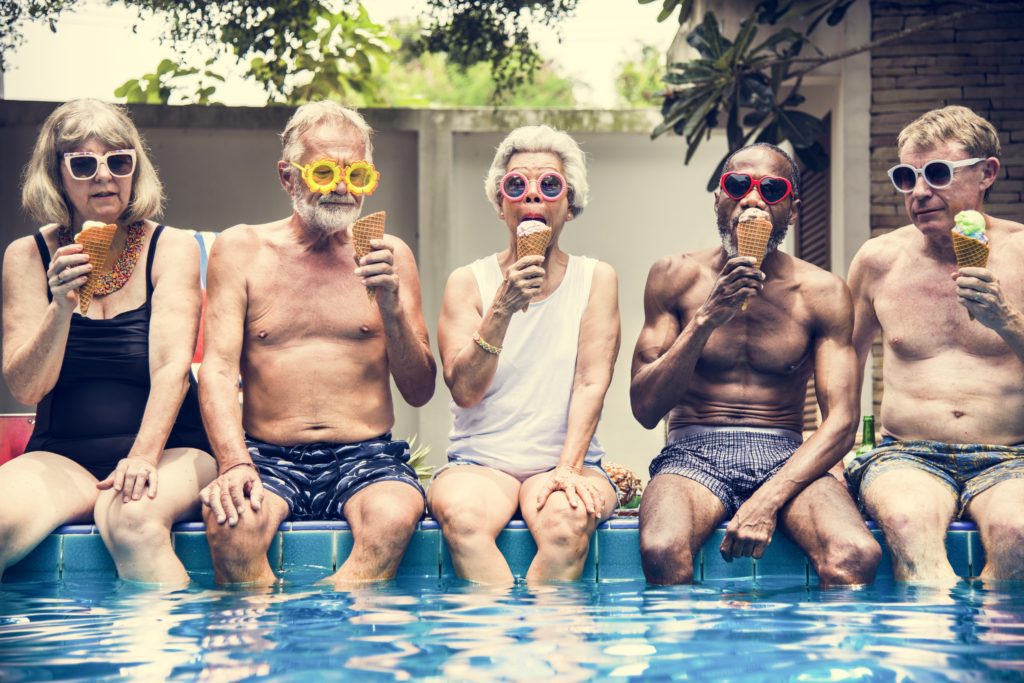 Older people by the pool enjoying ice cream with sunscreen